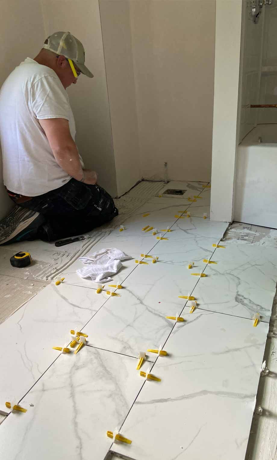 Joshua Caron from Caron Home Remodeling installing a bathroom tile floor.